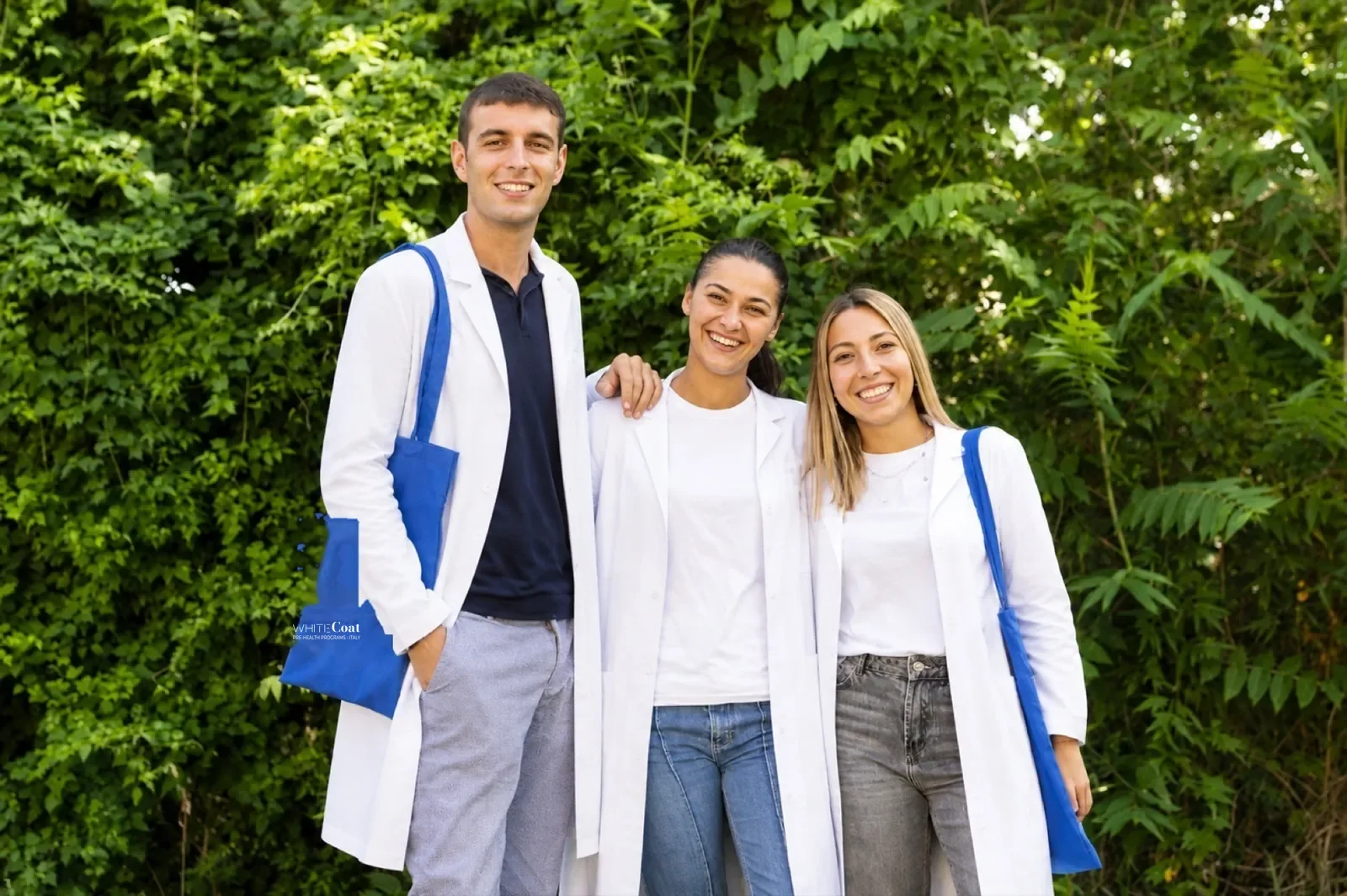 Three pre-health students in white coats on the Unicollege campus